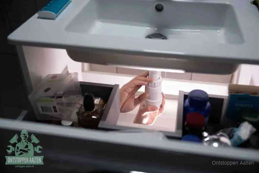 Een pompfles met zeep boven een wastafel, de heet water en afwasmiddel-methode om een vetprop in de afvoer los te maken in Aalten