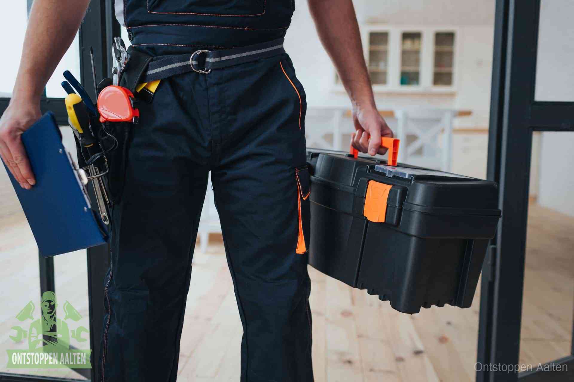 Een monteur met gereedschapsriem en klembord, klaar om een transparante prijs voor het wc ontstoppen in Aalten te geven