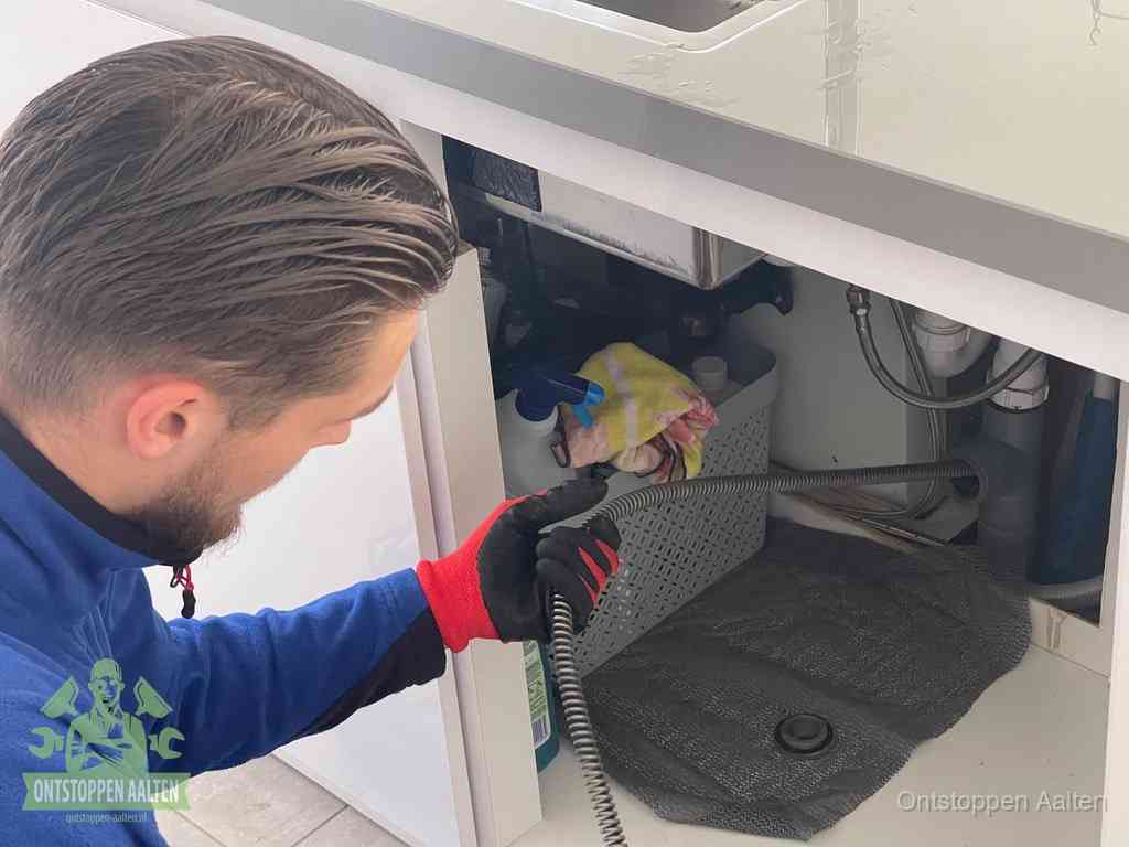 Een monteur voert een flexibele ontstoppingsveer in de afvoer om een verstopping voorbij de bocht van het toilet te bereiken in Aalten