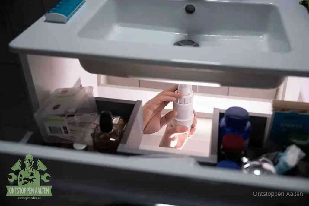 Een pompfles met zeep boven een wastafel in de toiletruimte, de warm water en afwasmiddel-methode om de wc te ontstoppen in Aalten