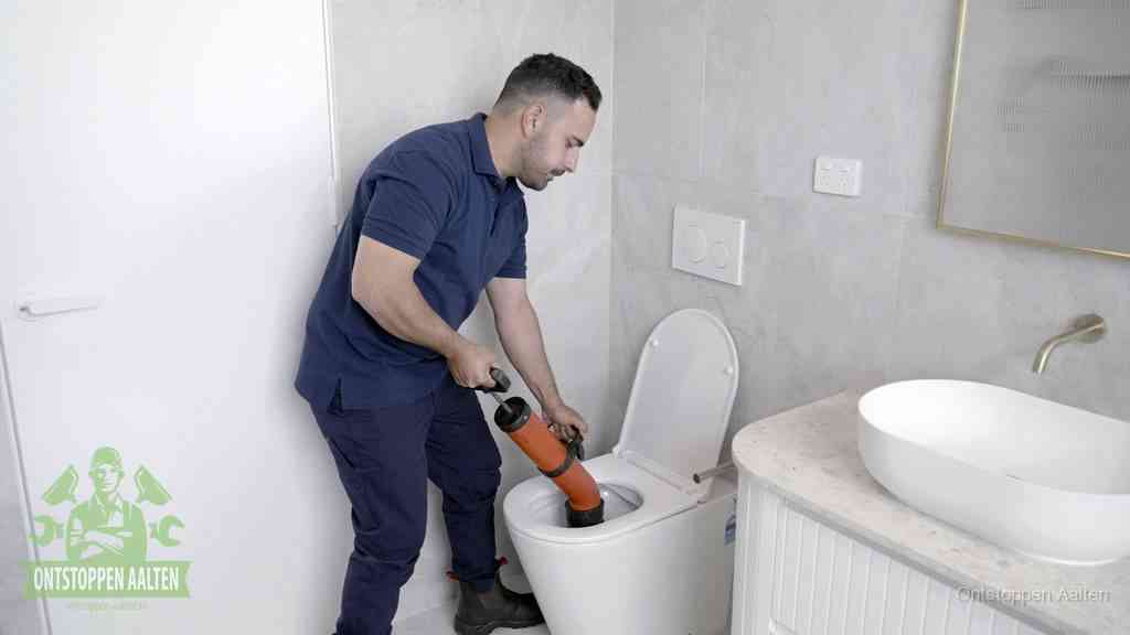 Een monteur gebruikt een handmatige perspomp (toiletontstopper) op een wandcloset tijdens het professioneel wc ontstoppen in Aalten